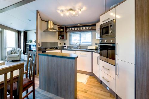 uma cozinha com armários brancos e uma bancada em Koie Holiday Home em Stranda