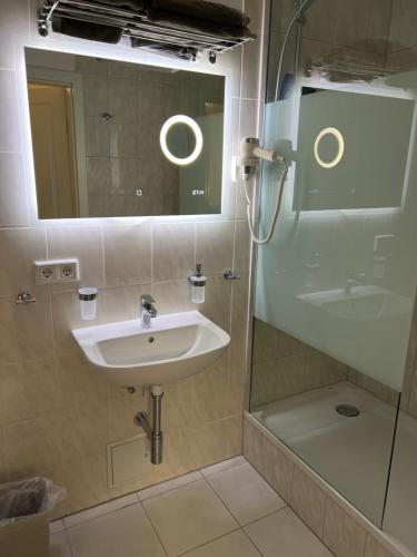 a bathroom with a sink and a shower with a mirror at Souterrain Studio-Apartment in Nuremberg
