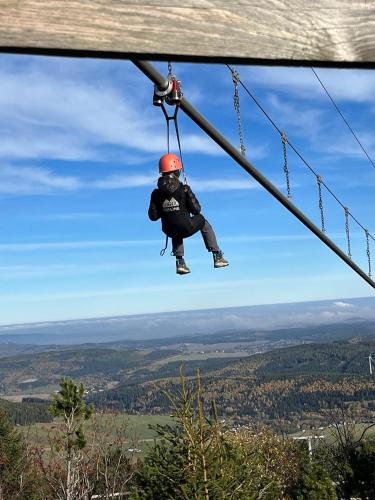 a person on a zip line in the sky at k1 sporthotel - Bike & Ski inklusive Hotel in Kurort Oberwiesenthal