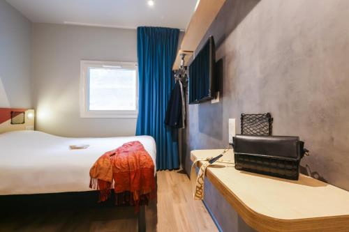 a hotel room with a bed and a desk and a window at ibis Budget Villemomble in Villemomble