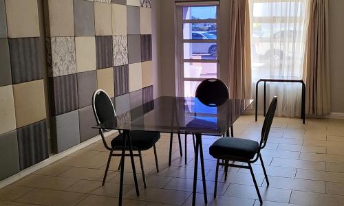 a glass table and chairs in a room with a window at SHALIMAR GARDENS HOTEL in Cape Town