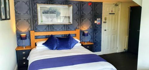 a bedroom with blue walls and a bed with blue pillows at The Clifton in South Shields