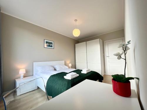 a bedroom with a bed with a green blanket at Garnizon by Q4Apartments in Gdańsk