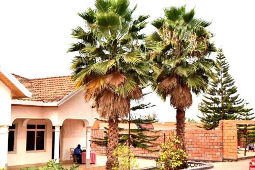two palm trees in front of a house at Room in BB - Martin Aviator Hotel in Kigali