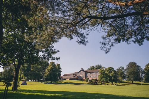 a house in a field with a tree in the foreground at Edenmore House in Craigavon