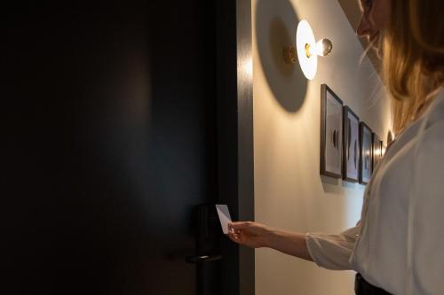 a woman is opening the door to a room at Boutique Hotel Helder I Kloeg Collection in Renesse