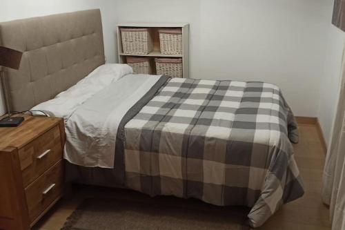 a bed with a checkered blanket next to a wooden cabinet at Ático en Paiporta con 2 grandes terrazas in Valencia