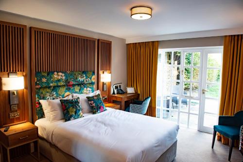 a hotel room with a large bed and a balcony at The Haycock Manor Hotel in Wansford