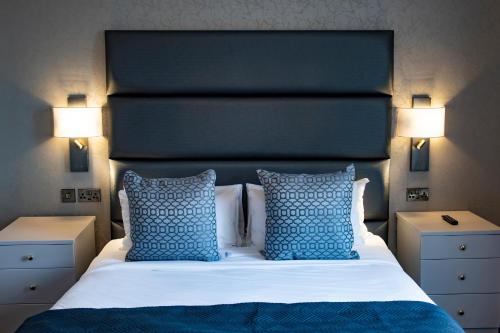 a bedroom with a large bed with blue pillows at The Haycock Manor Hotel in Wansford