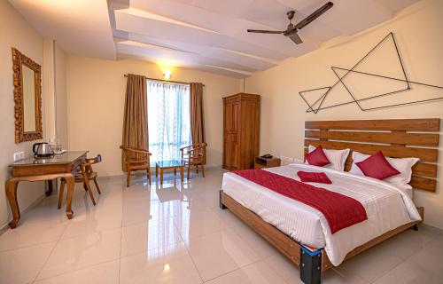 a bedroom with a bed and a table and a desk at Hotel SRM Grandeurs in Tudiyalūr