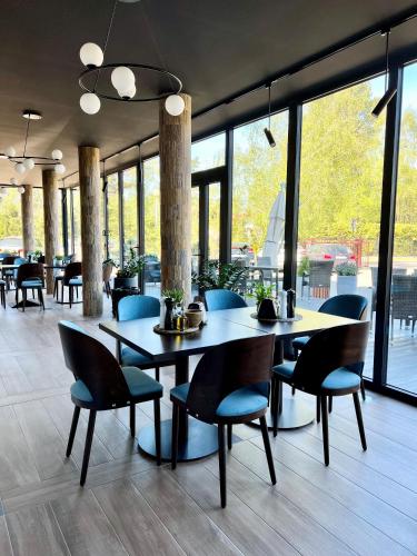 a dining room with tables and chairs and windows at BURSZTYN - BERNSTEIN SPA & Wellness in Dąbki