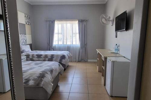 a small room with two beds and a mirror at SHALIMAR GARDENS HOTEL in Cape Town