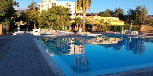 a swimming pool with a hotel in the background at Villaggio La Feluca in Isca sullo Ionio