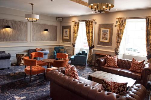 a living room with a leather couch and chairs at The Haycock Manor Hotel in Wansford