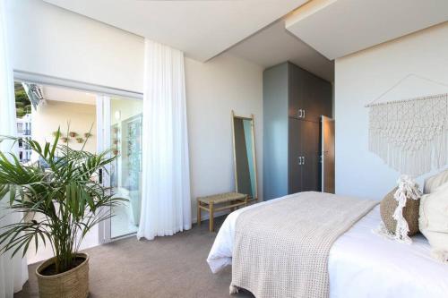 Un dormitorio con una cama blanca y una planta en The Number Collection 5103 en Ciudad del Cabo