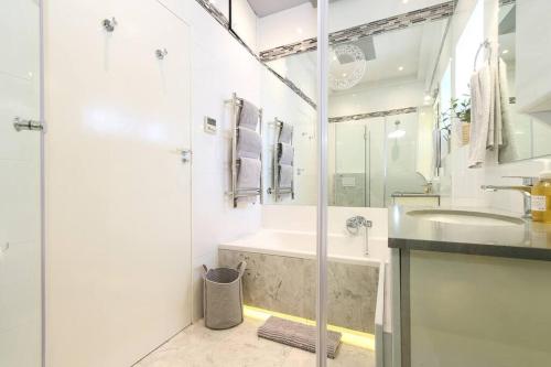 a white bathroom with a shower and a sink at The Number Collection 5103 in Cape Town