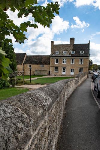 an old stone wall in front of a building at The Haycock Manor Hotel in Wansford
