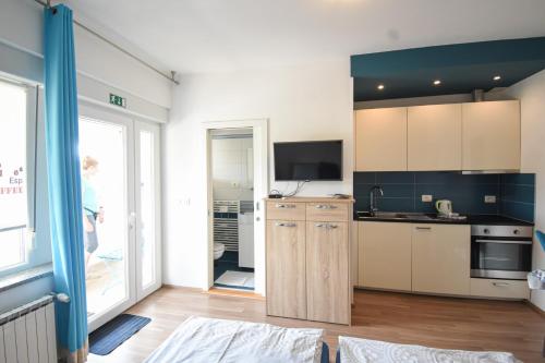 a kitchen with white cabinets and a tv on the wall at Apartmaji Sobe Zvezda in Pobegi