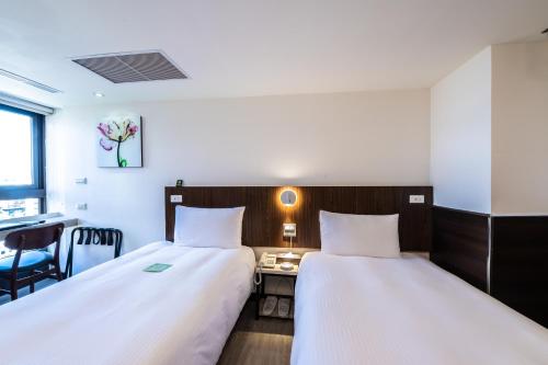 two beds in a hotel room with a desk and a desk at Hub Hotel - Songshan Airport Branch in Taipei