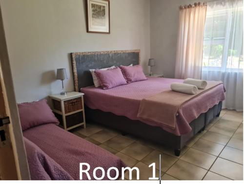 a bedroom with two beds with purple sheets and a window at Seagulls Nest in Port Edward