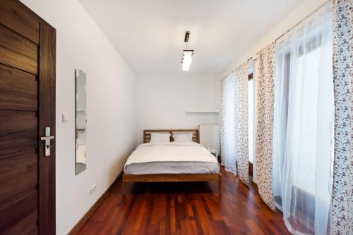 sypialnia z białymi ścianami i łóżkiem oraz drewnianą podłogą w obiekcie Malborska Lovely Apartment w Warszawie