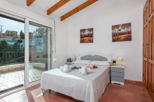 a white bedroom with a bed and a balcony at Villa Padilla - PlusHolidays in Benissa