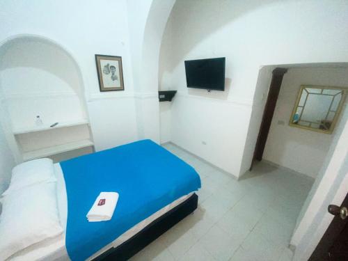 a bedroom with a blue bed and a tv at Hotel Mangata in Cartagena de Indias