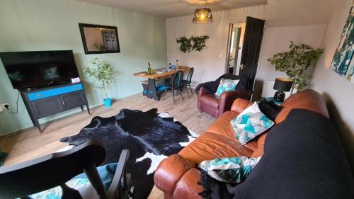 a living room with a couch and a tv and a table at The Farrier's by Spires Accommodation A convenient place to stay for exploring Cannock Chase in Hednesford