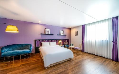a bedroom with a white bed and a blue chair at Hotel Hyggelig in Busan