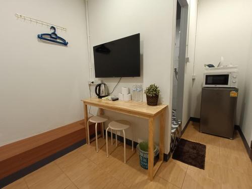 曼谷的住宿－My Home N1 - BTS Ratchathewi，小房间设有一张桌子、一台电视和一台冰箱