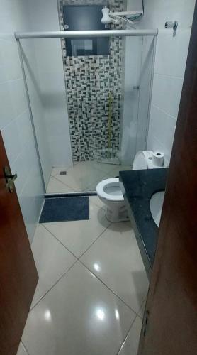 a bathroom with a toilet and a glass shower at Aconchego Familiar Veredas in Viçosa