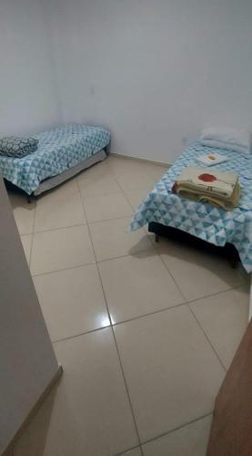two beds sitting on a tiled floor in a room at Aconchego Familiar Veredas in Viçosa
