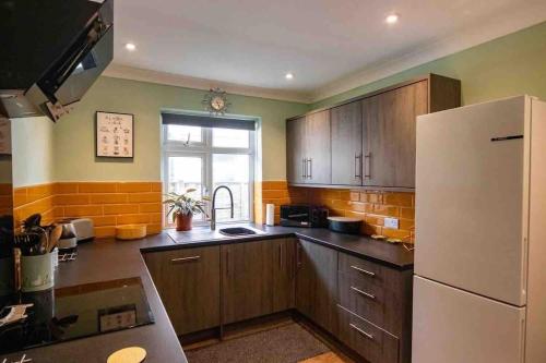 a kitchen with wooden cabinets and a white refrigerator at 1 Bedroom self contained apartment in Christchurch in Winkton