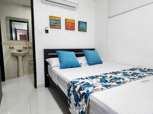 a bedroom with a bed with blue pillows and a sink at Apartamento frente a la playa 5B - By Bedviajes in Santa Marta