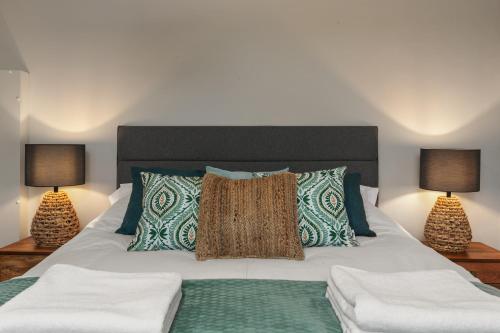 a bedroom with a white bed with two lamps at Golwg Y Môr - Sea View Cottage with Hot Tub in Saundersfoot