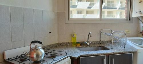 La cocina está equipada con fogones, fregadero y hervidor de agua. en Apartamento Pueyrredón en Córdoba