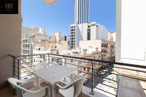 a table and chairs on a balcony with a view of the city at Spacious PV Apt close to clubs & schools with WIFI by 360 Estates in Paceville