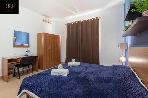 a bedroom with a blue bed and a desk at Spacious PV Apt close to clubs & schools with WIFI by 360 Estates in Paceville