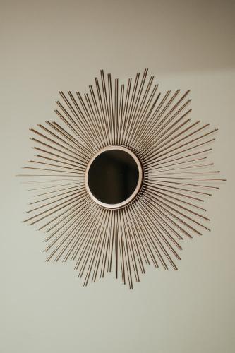 a metal sunburst mirror on a white wall at Emotional Grand Motel in Fontaneto dʼAgogna