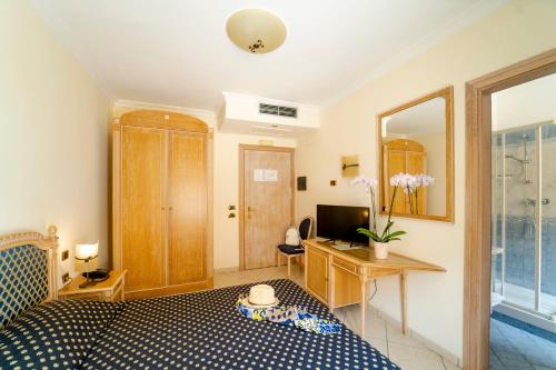 a bedroom with a bed and a desk and a mirror at Hotel Villa Romana in Porto Empedocle