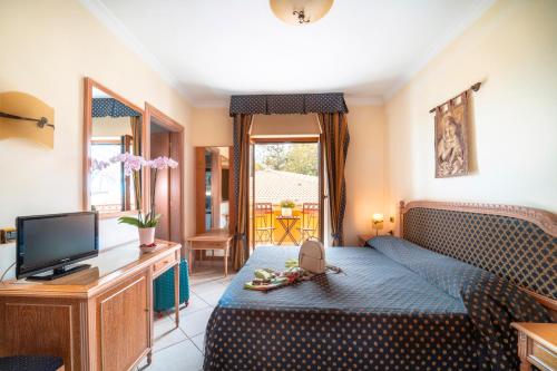 a bedroom with a blue bed and a television at Hotel Villa Romana in Porto Empedocle