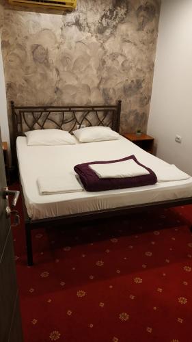 a bed with white sheets and pillows on it at Pensiunea Jolie in Iaşi