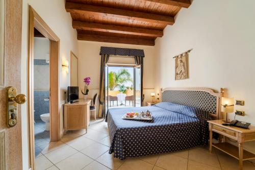 a bedroom with a blue bed and a bathroom at Hotel Villa Romana in Porto Empedocle