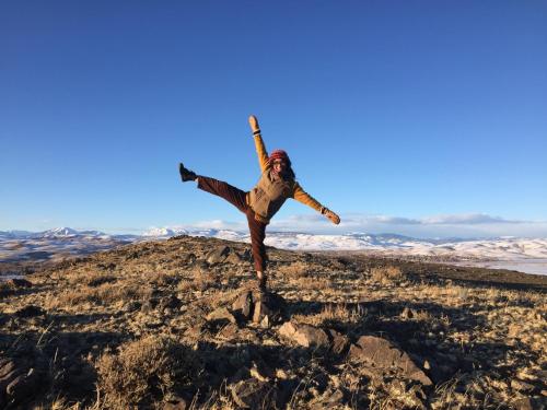 a man standing on a hill with his arms in the air at The Wanderlust Hostel in Gunnison