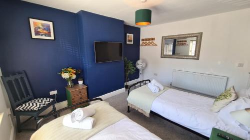 Habitación con 2 camas, TV y pared azul. en Worthingtons by Spires Accommodation A cosy and comfortable home from home place to stay in Burton-upon-Trent en Burton upon Trent