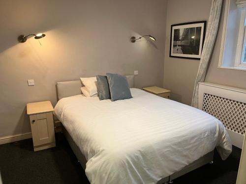 um quarto com uma cama com lençóis brancos e almofadas azuis em Lulus em St Bees
