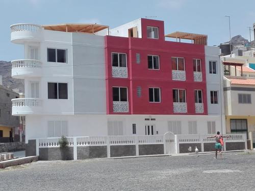 a red and white building with a person standing in front of it at Apart Laginha in Mindelo