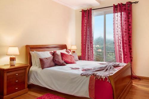 a bedroom with a bed with red curtains and a window at Vinháticos House in São Vicente