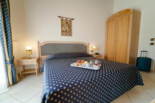 a blue and white bed with a tray of food on it at Hotel Villa Romana in Porto Empedocle