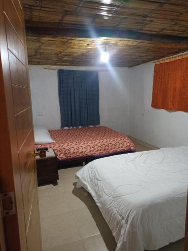 a room with two beds in a room with a wooden ceiling at Cabaña Eliseo Guachato Villa Rosita in Tota